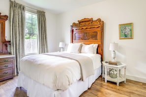 Classic bedroom with a large bed, bedside tables, and a dresser, featuring a framed floral painting.