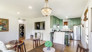 A spacious kitchen with green cabinets, a dining area with a wooden table, and a chandelier. - Large Yard: 'Pascagoula Peach' Home in Baton Rouge (Baton Rouge)