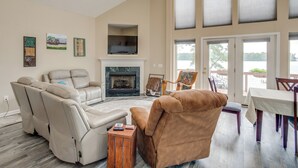 A spacious living room with a fireplace, comfortable seating, and large windows offering a view of the outdoors. - Deck & Views: Lake Murray Escape in Chapin! (Chapin)