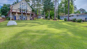 A two-story house with a covered porch, a small deck, and a large lawn. - Deck & Views: Lake Murray Escape in Chapin! (Chapin)