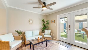 Un salon avec des meubles en osier, un ventilateur de plafond et une vue sur l’extérieur.