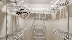 Un placard de rangement doté d’étagères métalliques et de barres pour suspendre les vêtements, aménagé de manière à optimiser l’espace de stockage.