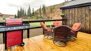 Eine Holzterrasse mit Grill und Korbstühlen.
