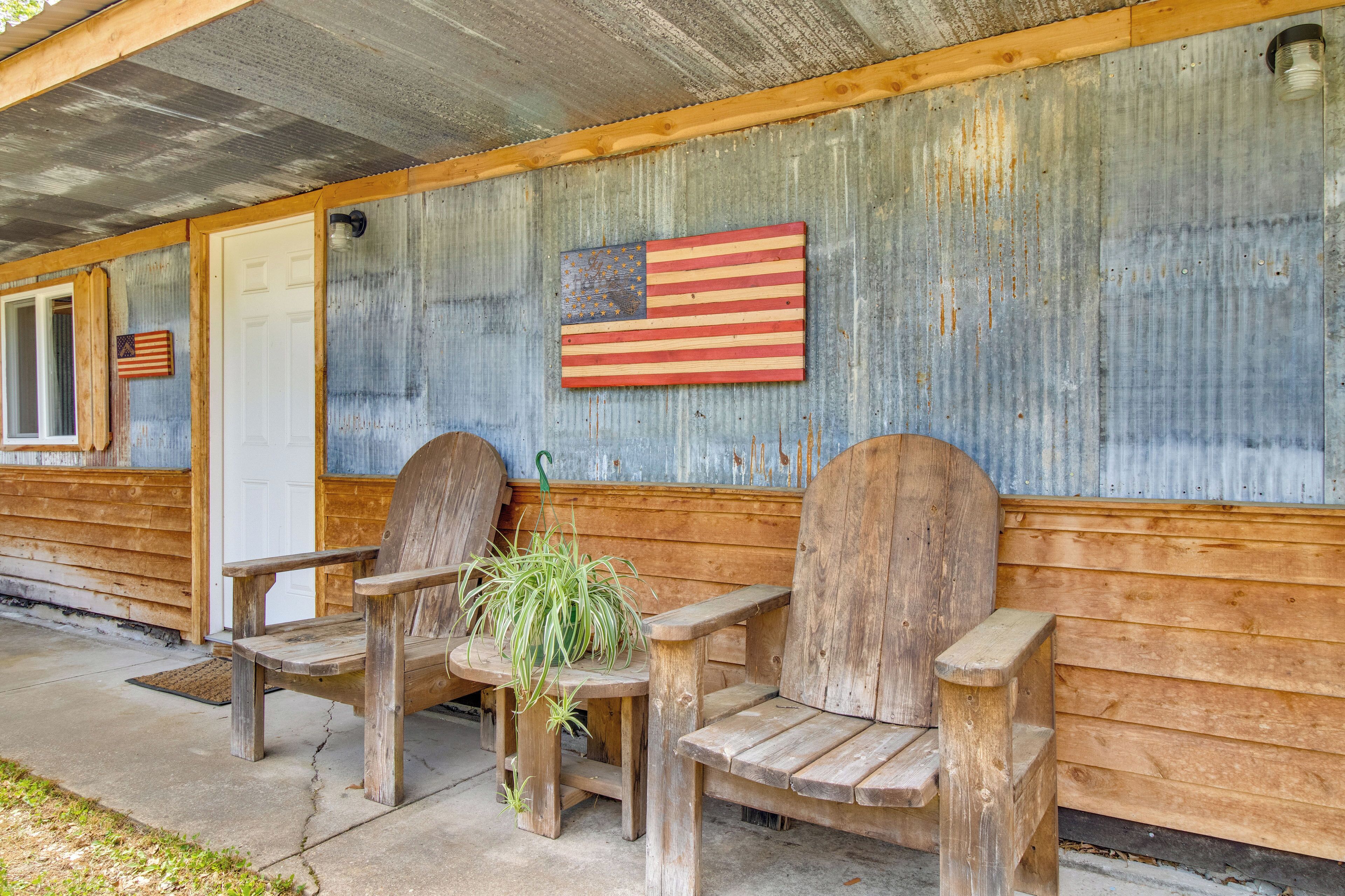 Een rustieke hut met houten banken en twee Amerikaanse vlaggen op de buitenmuur.