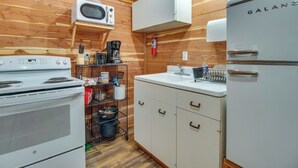 Una cocina compacta con estufa blanca, microondas, refrigerador blanco y armarios de madera.
