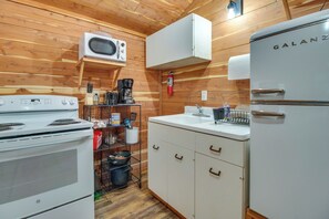 Une cuisine compacte équipée d’une cuisinière blanche, d’un four à micro-ondes et d’un réfrigérateur Galanz.