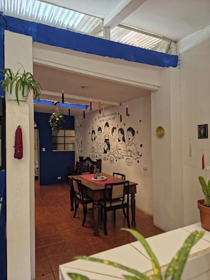 Un espace repas comprenant une table, des chaises et une fresque murale.