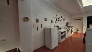 Una cocina funcional con refrigerador, lavamanos y un pequeño comedor.