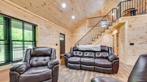 Un intérieur en bois avec un canapé en cuir, un fauteuil en cuir et un escalier.