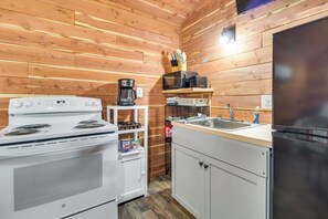 A kitchen with wooden walls, a white stove, a microwave, a sink, and a refrigerator. - Half-Mi to Bull Shoals Lake Access: Angler's Cabin (Lakeview)