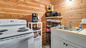 A compact kitchen with a white stove, a microwave, a coffee maker, and a sink. - Half-Mi to Bull Shoals Lake Access: Angler's Cabin (Lakeview)