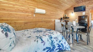 A wooden-paneled room with a bed, a small dining table, chairs, a TV, and a refrigerator. - Half-Mi to Bull Shoals Lake Access: Angler's Cabin (Lakeview)
