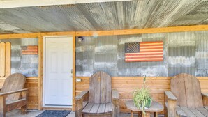 A wooden porch with two Adirondack chairs and a small table with a potted plant. - Half-Mi to Bull Shoals Lake Access: Angler's Cabin (Lakeview)