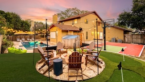 Un jardin avec une piscine, un espace salon extérieur et un terrain de basket-ball.
