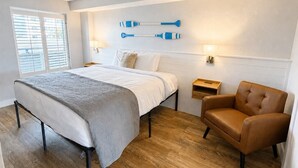 A bedroom with a bed, a chair, a nightstand, and a wall-mounted lamp. - Boardwalk Breeze! Premium Location (Myrtle Beach)