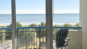 A balcony with a view of the beach, a chair, and a door leading to the outside. - Sunset Hollow/Premium Location (Myrtle Beach)
