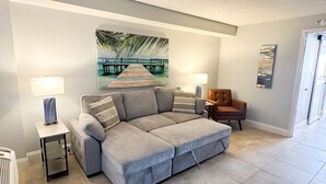 A living room with a sectional sofa, two side tables with lamps, a brown armchair, and a large abstract painting on the wall. - Sunset Hollow/Premium Location (Myrtle Beach)