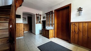 Un pasillo con paneles de madera, suelo de baldosas, una puerta de madera y un perchero con ganchos.