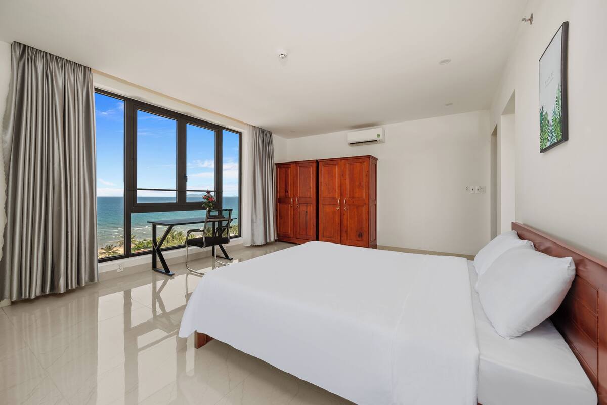 Una camera da letto con un letto grande, una scrivania e vista sull'oceano.