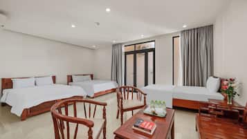 A hotel room with two beds, wooden furniture, a small table with a book, and a window with curtains.