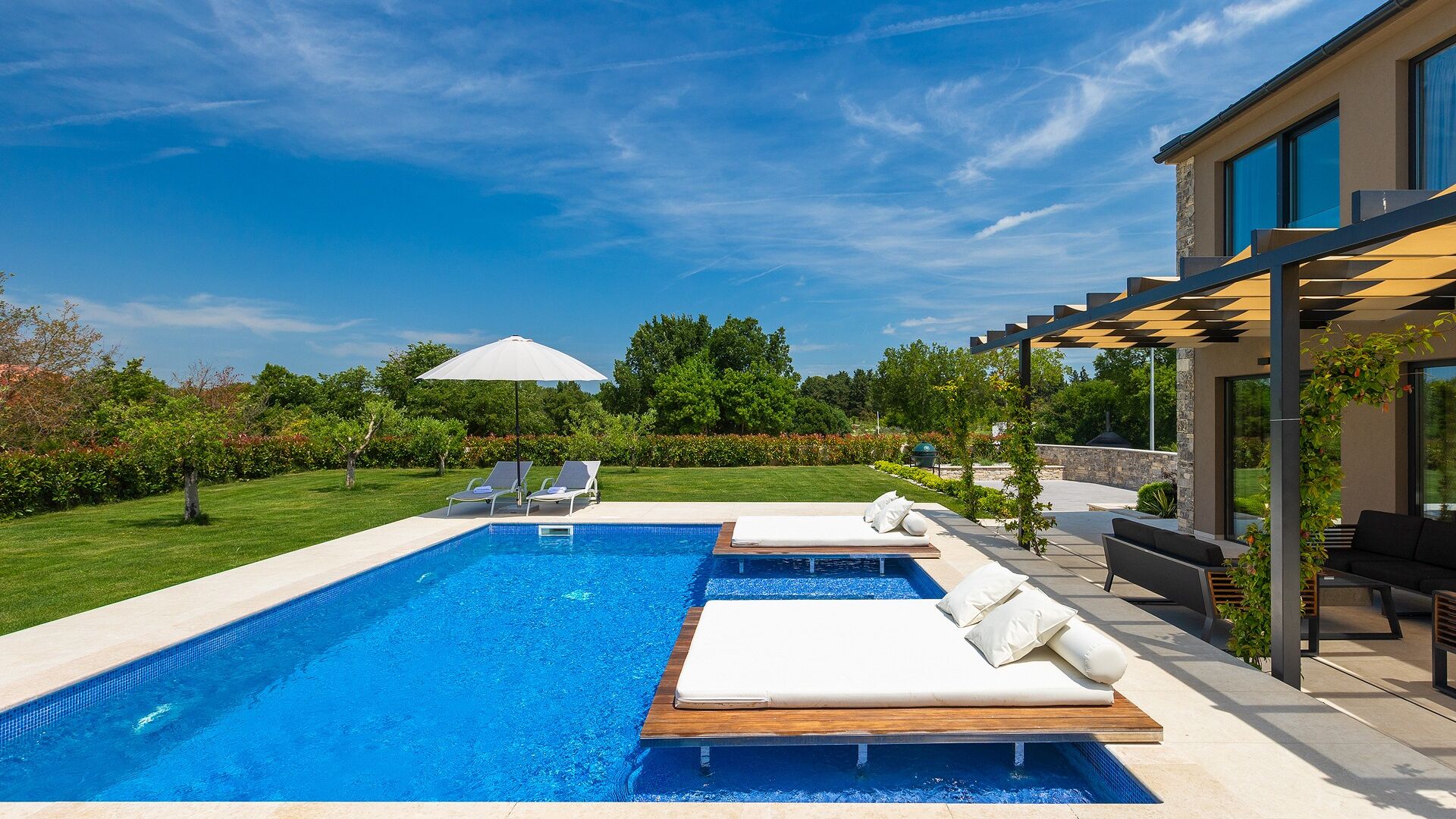A modern outdoor pool area with lounge chairs and a pergola.