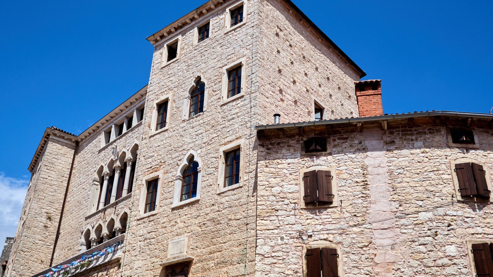 A stone building with multiple windows and a balcony.