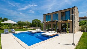 A modern house with a swimming pool, outdoor seating, and a pergola.
