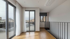 En moderne lejlighed med store skydedøre af glas, trægulv og en balkon med gelænder af metal.
