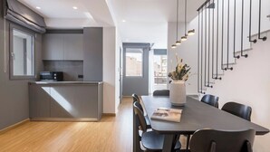 Et moderne køkken med lysegrå skabe, en indbygget mikroovn og et spiseområde med et mørkt bord og stole.