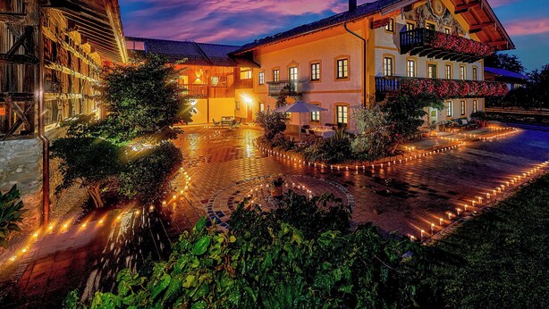 Un edificio tradicional con patio, mesas al aire libre y una entrada bien iluminada.
