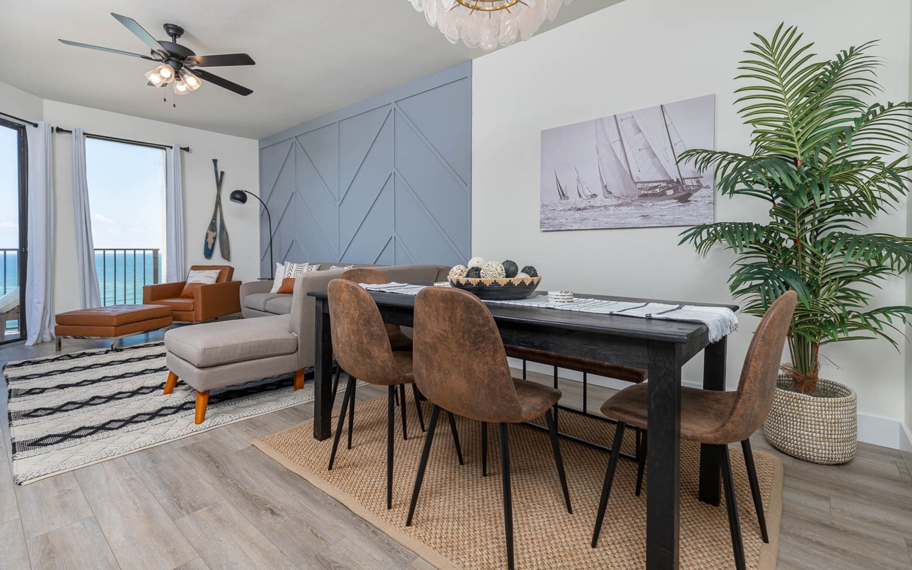 A modern living room with a sofa, chairs, a dining table, and a large potted plant.
