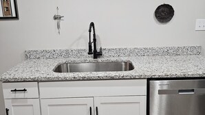 A kitchen with white cabinets, a stainless steel sink, and a dishwasher.