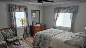 A bedroom with a bed, a rocking chair, a dresser, a mirror, and a floor lamp.
