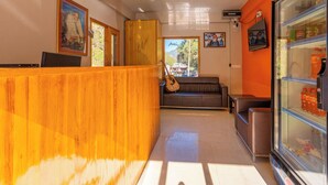 Un área de recepción con mostrador de madera, un sofá y un refrigerador lleno de bebidas.