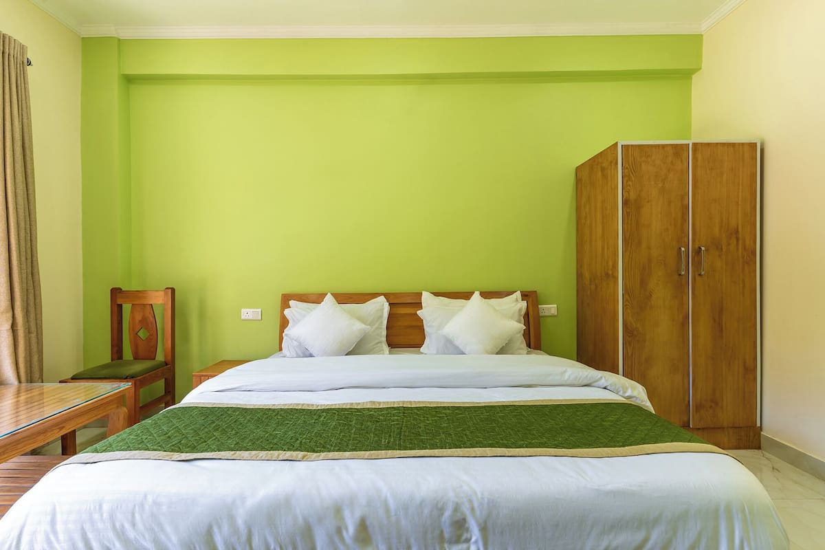 Un dormitorio con una cama, un armario de madera y una silla.