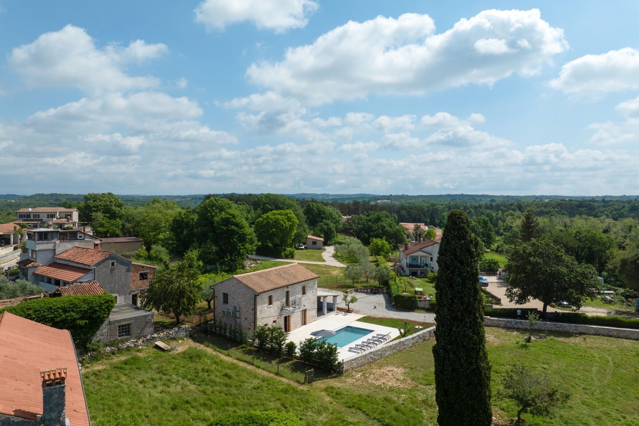 Un quartier résidentiel avec une piscine, des maisons et un grand arbre.