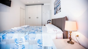 A bedroom with a bed, a bedside table with a lamp, a wardrobe, and a painting on the wall. - Benzi16 (Como)