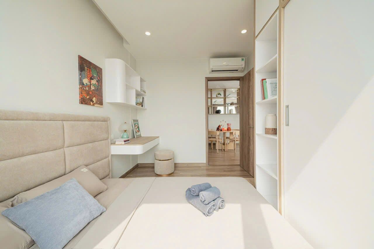 A modern bedroom with a bed, a bedside table, a small stool, and a wardrobe.