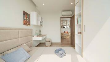 A modern bedroom with a bed, a bedside table, a small stool, and a wardrobe.