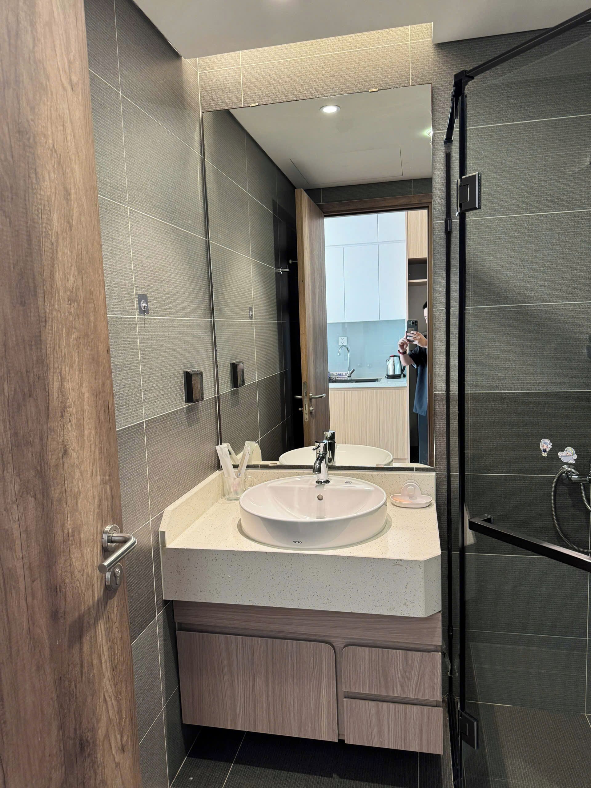 A modern bathroom with a large mirror, two sinks, and a shower area.