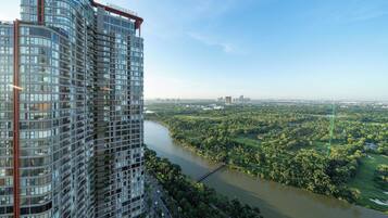 A high-rise building with a curved facade, a river in the foreground, and a distant cityscape.