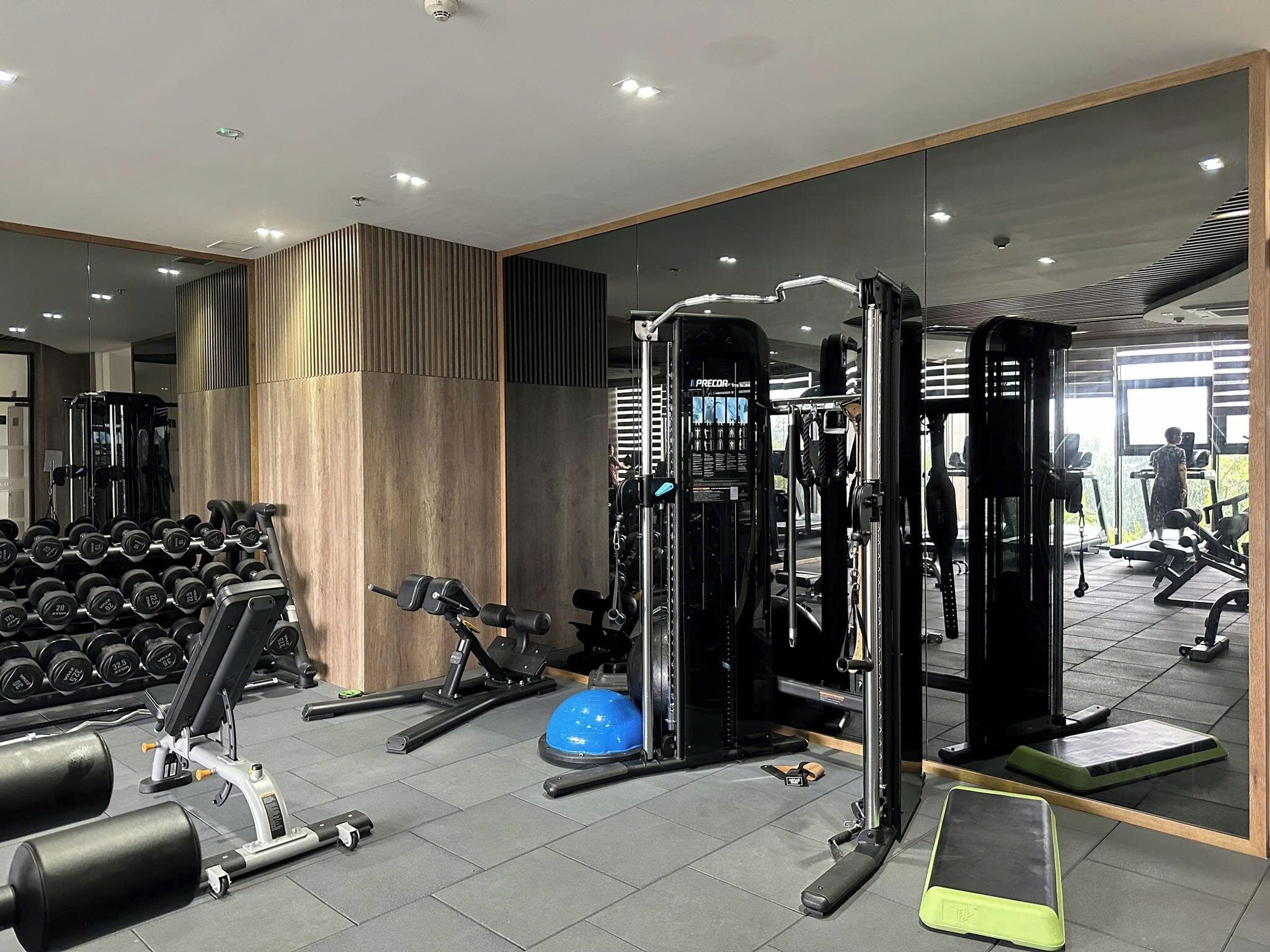 Une salle de sport moderne équipée de divers appareils d’exercice, notamment des haltères, un support à squats et un ballon lesté.