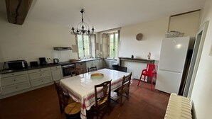 A kitchen with a dining table, chairs, a chandelier, and a refrigerator.