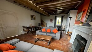 A living room with a grey sofa, orange cushions, a wooden coffee table, and a fireplace.