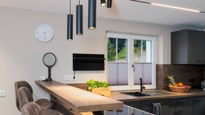 Una cocina moderna con encimera de madera, lavaplatos integrado y una ventana con persianas.