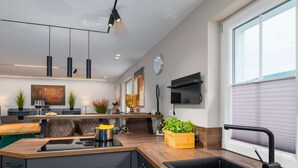 Una cocina moderna con una isla central, electrodomésticos integrados y un amplio ventanal con persianas.