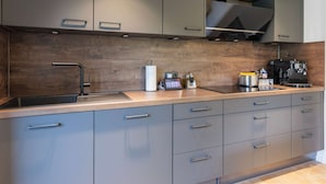 Una cocina moderna con armarios grises, un protector contra salpicaduras de madera y una cafetera integrada.