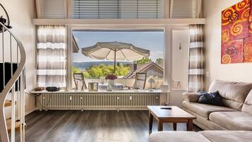 Un salon avec vue, un radiateur, un canapé, une table basse et une fenêtre avec des rideaux.