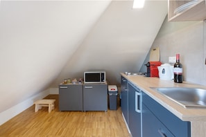 A compact kitchen with a microwave, refrigerator, and sink.