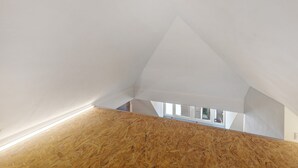 Un plafond en pente avec un lambris en bois et un puits de lumière.